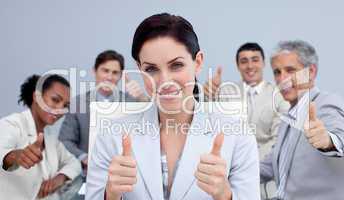 Businesswoman and her team with thumbs up in a meeting