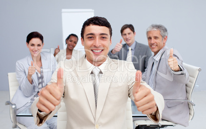 Attractive businessman and his team with thumbs up
