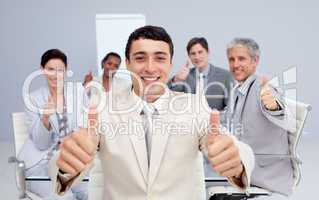 Attractive businessman and his team with thumbs up