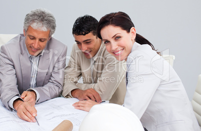 Portrait of a female engineer studying plans with her colleagues