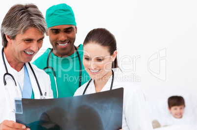 Medical team examining an x-ray and a little boy in bed