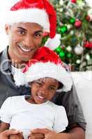Afro-American dad and daughter wearing a Christmas hat