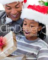 Portrait of an Afro-American father and son opening a Christmas