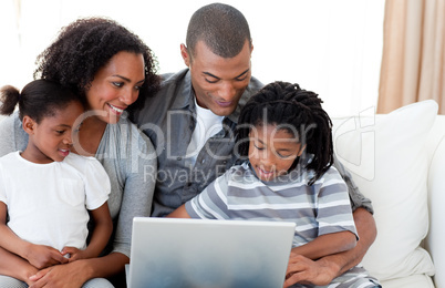 Afro-American family using a laptop on the sofa