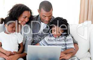 Afro-American family using a laptop on the sofa