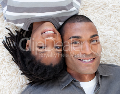 Smiling Afro-American father and son lying on the floor
