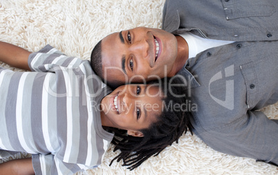 Smiling Afro-American father and son relaxing on the floor