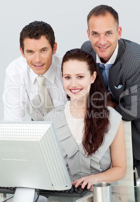 Smiling three business people using a computer