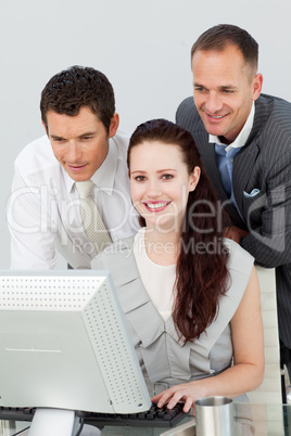 Smiling businesswoman and two businessmen using a computer