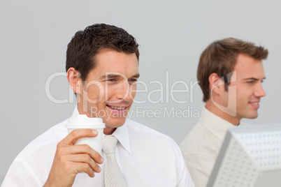 Businessman drinking coffee in the office while he is using the