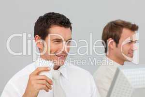 Businessman drinking coffee in the office while he is using the