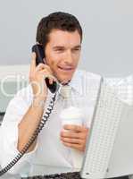 Attractive businessman on phone drinking a coffee in the office