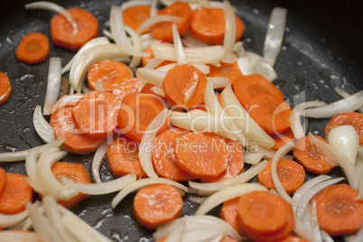 Karotten und Zwiebeln werden in der Pfanne angebraten