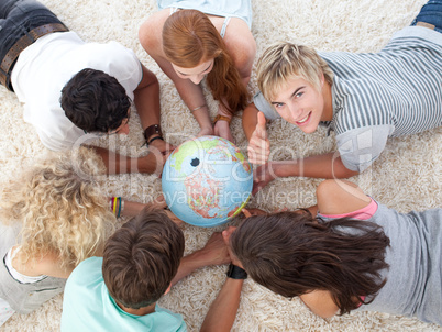 Group of teenagers on the floor examining a terrestrial world an