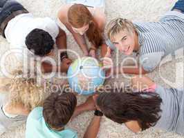 Group of teenagers on the floor examining a terrestrial world an