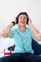 A teenage guy sitting on his bed listening to the music