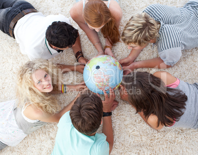 High angle of teenagers on the floor examining a terrestrial wor