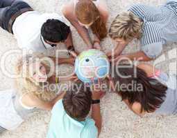 High angle of teenagers on the floor examining a terrestrial wor