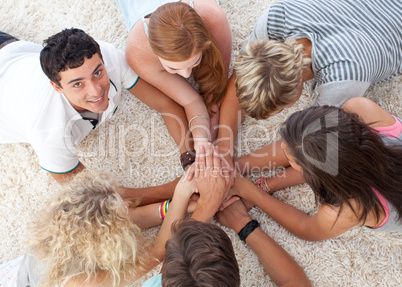 Teenagers lying on the ground with hands together