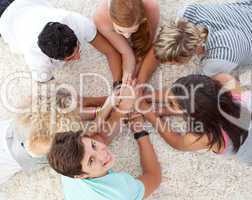 Teenagers lying on the floor with hands together