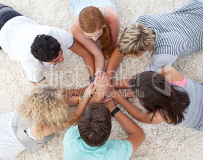Teenagers lying on the floor with hands together