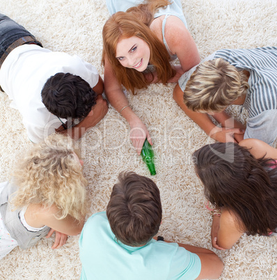 Group of friends playing spin the bottle on the floor