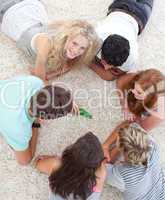 Group of teenagers playing spin the bottle on the floor