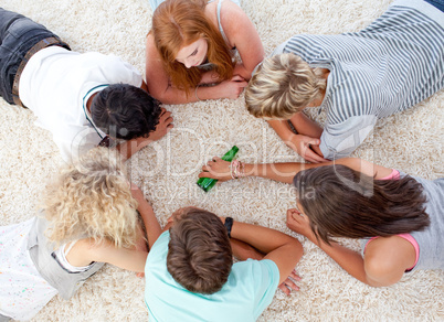 Group of teenagers playing with a bottle on the floor