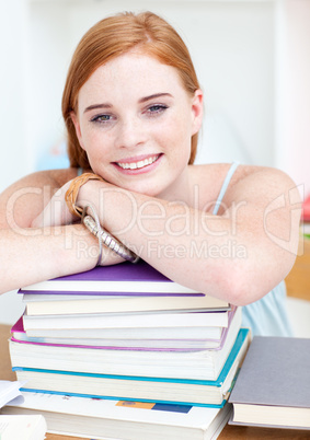 Smiling teeenager studying lots of books