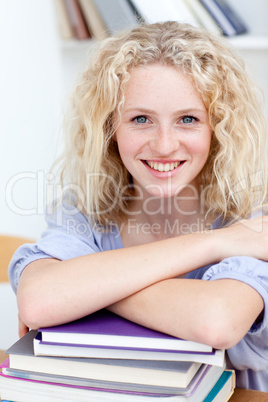 Smiling teeenager studying lots of books