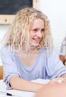 Smiling blonde teenager doing homework in a library