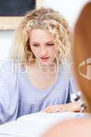 Blonde teenager doing homework in a library