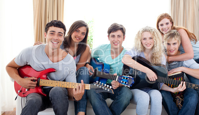 Group of teenagers playing guitar at home