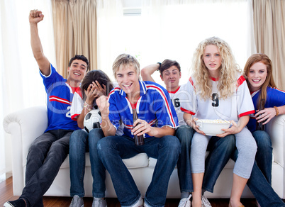 Teenagers watching a football match in the living-room