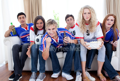 Teenagers watching a football match at home