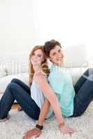 A smiling couple of teenagers sitting on the floor