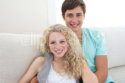 Happy couple of teens sitting on the sofa