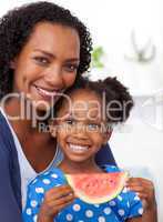 Smiling mother and her daughter eating fruit