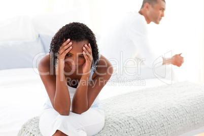 Upset Afro-american couple sitting on bed separately