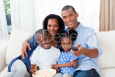 Smiling Afro-american family eating popcorn and watching TV