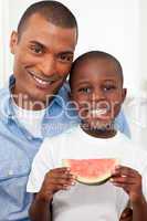 Portrait of a smiling boy eating fruit with his father