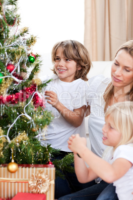 Happy mother and her children hanging Christmas decorations