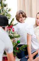 Happy parents and their children decorating a Christmas tree