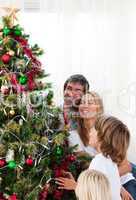 Smiling family decorating a Christmas tree