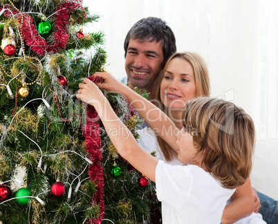 Little boy hanging Christmas decorations with his parents