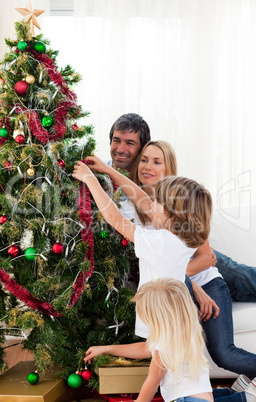 Smiling family hanging decorations on a Christmas tree