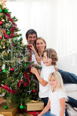 Parents and their children decorating a Christmas tree