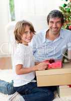 Smiling father and his son opening Christmas presents