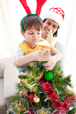 Father and son putting a star on the top of a Christmas tree