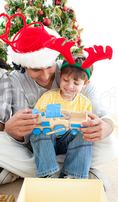 Happy child playing with a train with his father
